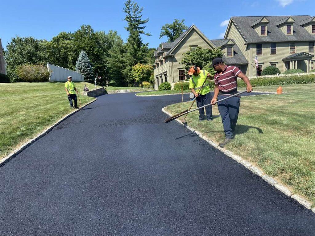 A Team Asphalt crew raking fresh hot mix asphalt on a driveway